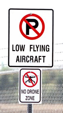 Pistin sonundaki alçaktan uçan uçak yüzünden iki sokak tabelası park yeri olmadığını ve İHA 'nın uçmadığını gösteriyor..