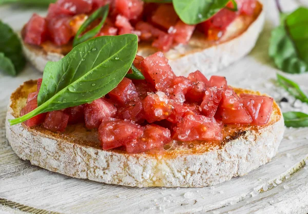 Tomato bruschetta on rustic light wooden board. Healthy snack or appetizer with wine
