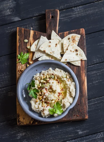 Healthy vegan cauliflower hummus and homemade tortilla on a dark rustic cutting board on a dark background. Delicious healthy snack