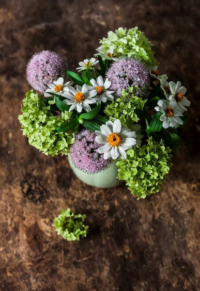 Bouquet of summer flowers of hydrangeas, daisies on a wooden background, top view