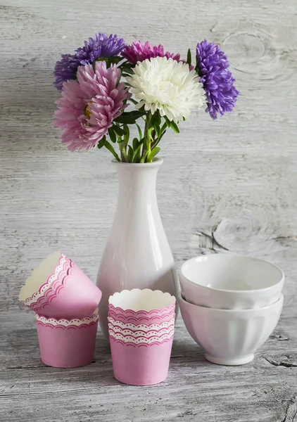 autumn flowers asters in a white vase, ceramic bowls and paper molds for baking cakes
