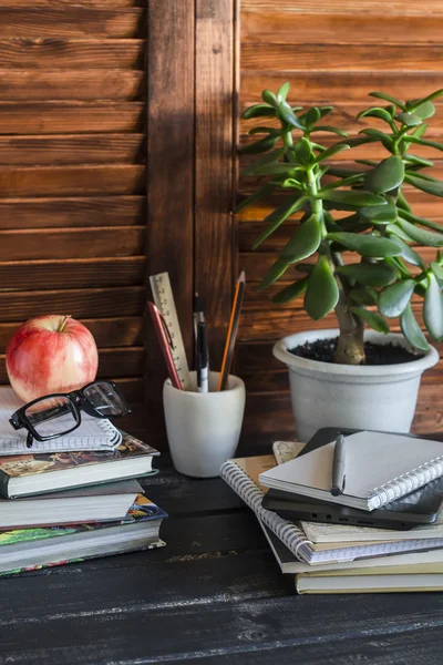 Home workspace  and accessories for work, training and education - books, magazines, notebooks, notepads, pens, pencils, tablet, glasses, and a healthy snack apple