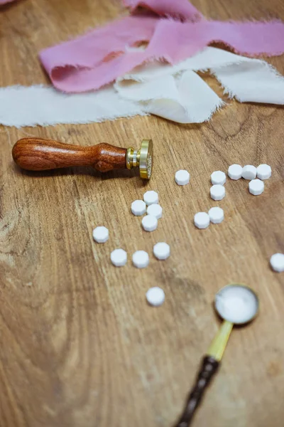 Vintage wax seal stamp lies on a wooden table. Golden spoon and pieces of wax