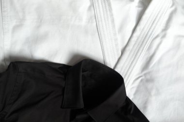 Karate eğitimi için beyaz kimono. Yanında siyah klasik bir gömlek var.