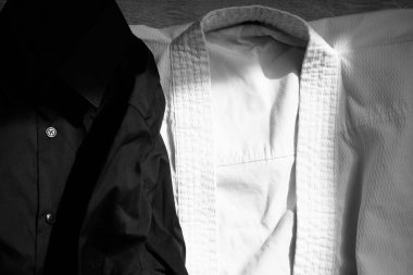 Karate eğitimi için beyaz kimono. Yanında siyah klasik bir gömlek var.