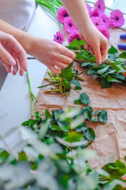 Bıçakla yeşil ve pembe çiçekleri kesen birinin elleri.