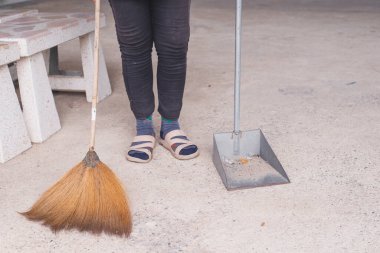 Ev hanımı elinde bir faraş tutuyor ve evi süpürüyor.