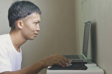 Laptop oynayan genç Asyalı adam.