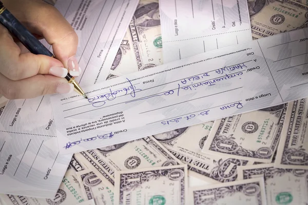 Manager signed a check on a desk full of dollars — Stock Photo, Image