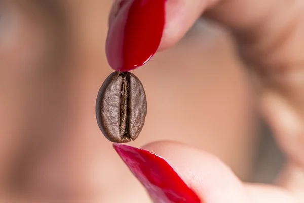 Coffee bean between red nail polish Royalty Free Stock Images