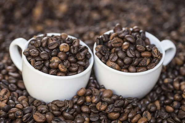 Xícaras cheias de grãos de café em grãos de café — Fotografia de Stock