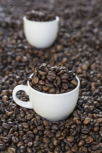 Tazas llenas de granos de café en granos de café —  Fotos de Stock