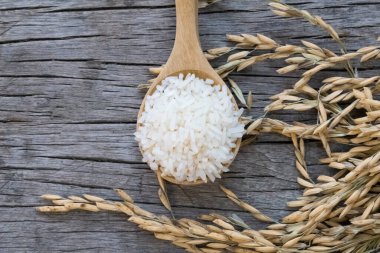 Tahta arka planda pirinç. Yasemin pilavı eski ahşap bir masada tahta bir kaşığa konur..