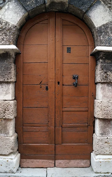 Dřevěné dveře kostela v kamenným obloukem — Stock fotografie