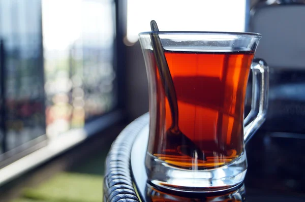 Un verre de thé rouge avec une cuillère à la table ronde — Photo
