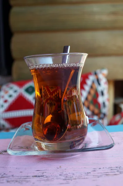 Turkish tea in a glass on a background of wooden logs — Stock Photo, Image