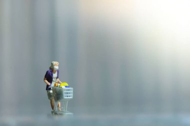 Tek başına süpermarkette maske takan bir kadın. Minyatür insanlar oyuncakları kavramsal fotoğrafçılık olarak tasvir ederler..