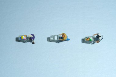 İnsanlar bakkaliye parasını ödemek için kasiyere mesafelerini koruyarak sıraya giriyorlar. Minyatür insanlar oyuncakları kavramsal fotoğrafçılık olarak tasvir ederler..