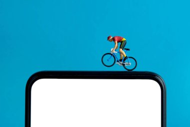 Bisiklet eğitmeni ve izleme uygulaması. Akıllı telefonun üstünde bir bisiklet. Minyatür insanlar kavramsal fotoğrafçılığı şekillendirir.