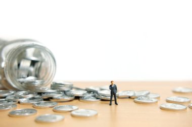 Bir şişeden saçılan paraları izleyen iş adamları. Minyatür insanlar kavramsal fotoğrafçılığı şekillendirir.