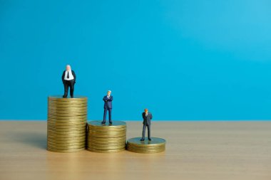 Minyatür iş konsepti - işadamı altın para yığınının üzerinde duruyor