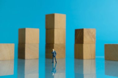 Minyatür iş konsepti - genç iş adamının ahşap çizelgenin önünde durması