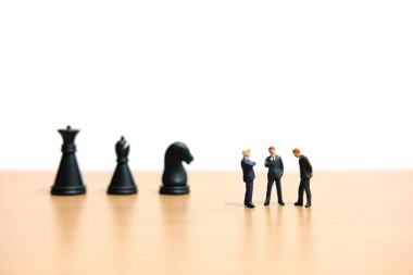 İş stratejisi kavramsal fotoğrafı - Satranç Şövalyesi önünde bir grup minyatür iş adamı tartışması