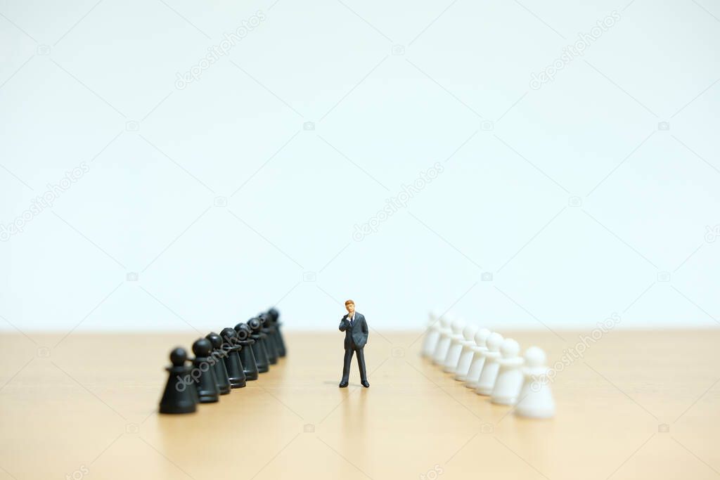 Miniature people strategic concept - businessman thinking in between of chess pieces line