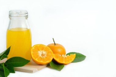 Ahşap altlığın üstünde taze portakal suyu, çiğ, dilimlenmiş portakal meyvesi, beyaz arka planda stüdyo ışıklandırmasıyla izole edilmiş.