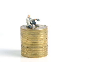 Minyatür minyatür insanlar fotoğraf çekmeyi sever. Fakir bir adam ya da bir dilenci, beyaz arka planda izole edilmiş altın para yığınının üzerinde oturur.