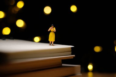 Evde eğitim, gece karantina ya da tecrit saatleriyle ilgili kitap okuyan çocuklar. Minyatür minyatür insanlar Bokeh ışıklı arka planda fotoğraf çekiyorlar.