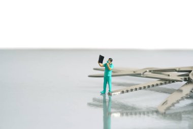 Minyatür insanlar oyuncak fotoğrafçılık. Röntgen sonuçlarına bakan bir erkek doktor ya da hemşire, beyaz arka planda izole edilmiş cerrahi ekipmanlarla sonuçlanır. Resim fotoğrafı.
