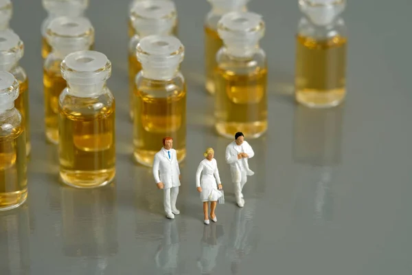 Miniature people toy figure photography. Vaccination distribution concept. A group of doctor walking in front of ampule vaccine vial. Image photo