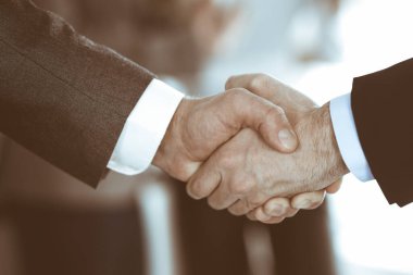 İş adamları toplantıdan ya da pazarlıktan sonra iş arkadaşlarıyla el sıkışıyorlar. Yakın plan. Modern ofisteki bir grup tanınmamış iş adamı ve kadın. Takım çalışması, ortaklık ve tokalaşma