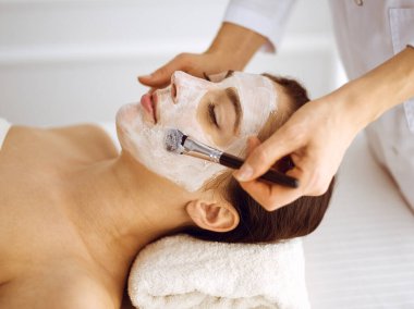 Güzel esmer kadın kapalı gözlerle kozmetik maske takmaktan zevk alıyor. Tıp ve kaplıca merkezi kavramlarında rahatlatıcı tedavi