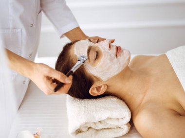 Güzel esmer kadın kapalı gözlerle kozmetik maske takmaktan zevk alıyor. Tıp ve kaplıca merkezi kavramlarında rahatlatıcı tedavi