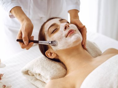 Güzel esmer kadın kapalı gözlerle kozmetik maske takmaktan zevk alıyor. Tıp ve kaplıca merkezi kavramlarında rahatlatıcı tedavi