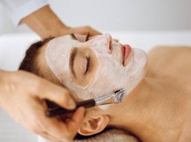 Güzel esmer kadın kapalı gözlerle kozmetik maske takmaktan zevk alıyor. Tıp ve kaplıca merkezi kavramlarında rahatlatıcı tedavi