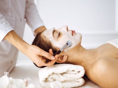 Güzel esmer kadın kapalı gözlerle kozmetik maske takmaktan zevk alıyor. Tıp ve kaplıca merkezi kavramlarında rahatlatıcı tedavi