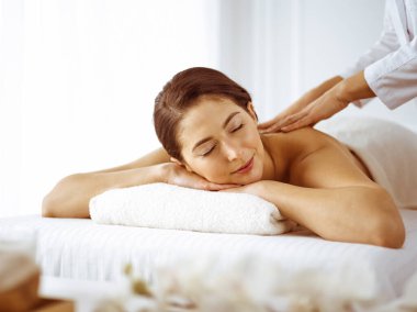 Güzel esmer kadın gözleri kapalı sırt masajından hoşlanıyor. Spa ve tıp konsepti