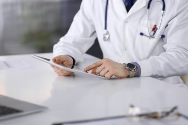 Bilinmeyen erkek doktor klinikteki tablet bilgisayarla yakın planda çalışıyor. İşteki genç doktor. Mükemmel sağlık hizmeti, tıp konsepti