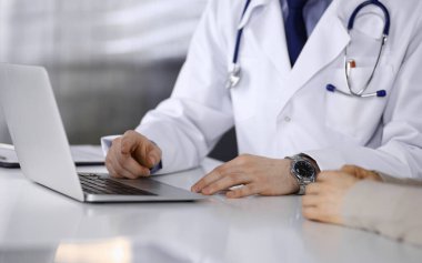 Bilinmeyen erkek doktor ve hasta kadın klinikte oturup dizüstü bilgisayar kullanırken bir şeyler tartışıyorlar. Hastanedeki en iyi sağlık hizmeti, ilaç, salgın durdurma.