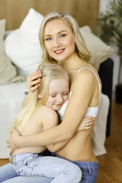 Happy mom and little daughter cuddle while dressing. Motherhood and family concept