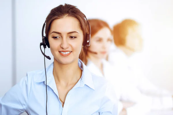 Opérateurs de centre d'appels. Focus sur belle femme d'affaires en utilisant casque dans le bureau ensoleillé Images De Stock Libres De Droits