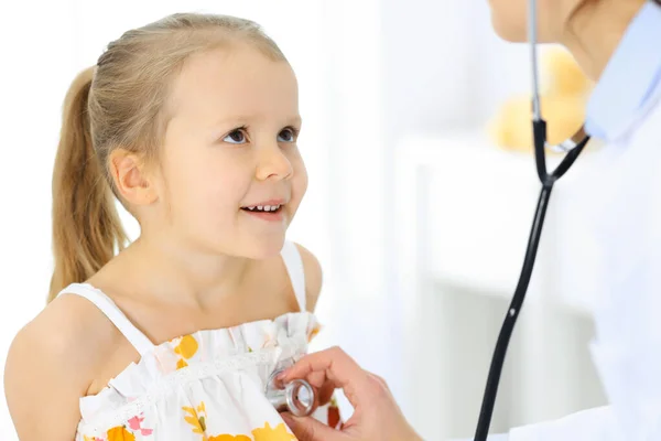 Doutor examinando uma menina por estetoscópio. Paciente de criança sorridente feliz em inspeção médica habitual. Conceitos de medicina e saúde — Fotografia de Stock