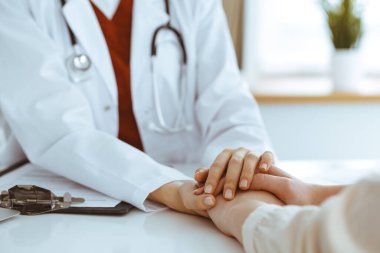 Kadın hastasına güvence veren kimliği belirsiz kadın doktorun elleri, yakın plan. Tıp konsepti