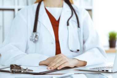 İş yerindeki masada oturan kimliği belirsiz kadın-doktor, ellerinizi yakın tutun. Tıp konsepti