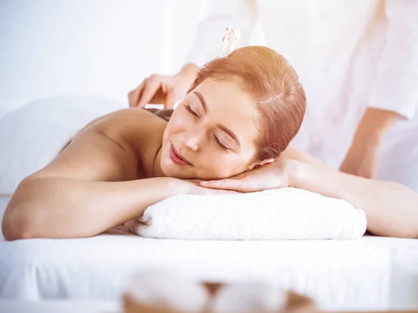 Hermosa mujer morena disfrutando de masaje de espalda en el centro de spa soleado. Concepto de belleza y medicina — Foto de Stock