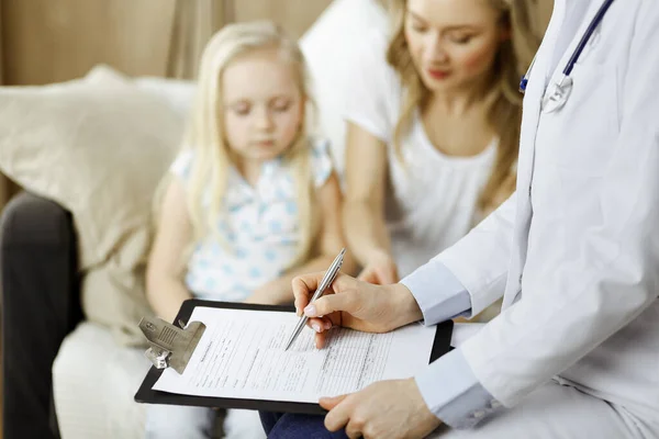 Dokter en patiënt. Kinderarts die klembord gebruikt terwijl ze het kleine meisje onderzoekt met haar moeder thuis. Ziek en ongelukkig kind bij medisch onderzoek. Geneesmiddelenconcept — Stockfoto