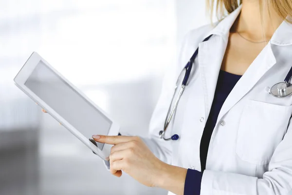 Neznámá žena-doktorka drží v rukou tablet, zatímco stojí ve skříni na klinice. Ženský lékař se stetoskopem, zblízka. Perfektní lékařská služba v nemocnici. Medicína — Stock fotografie